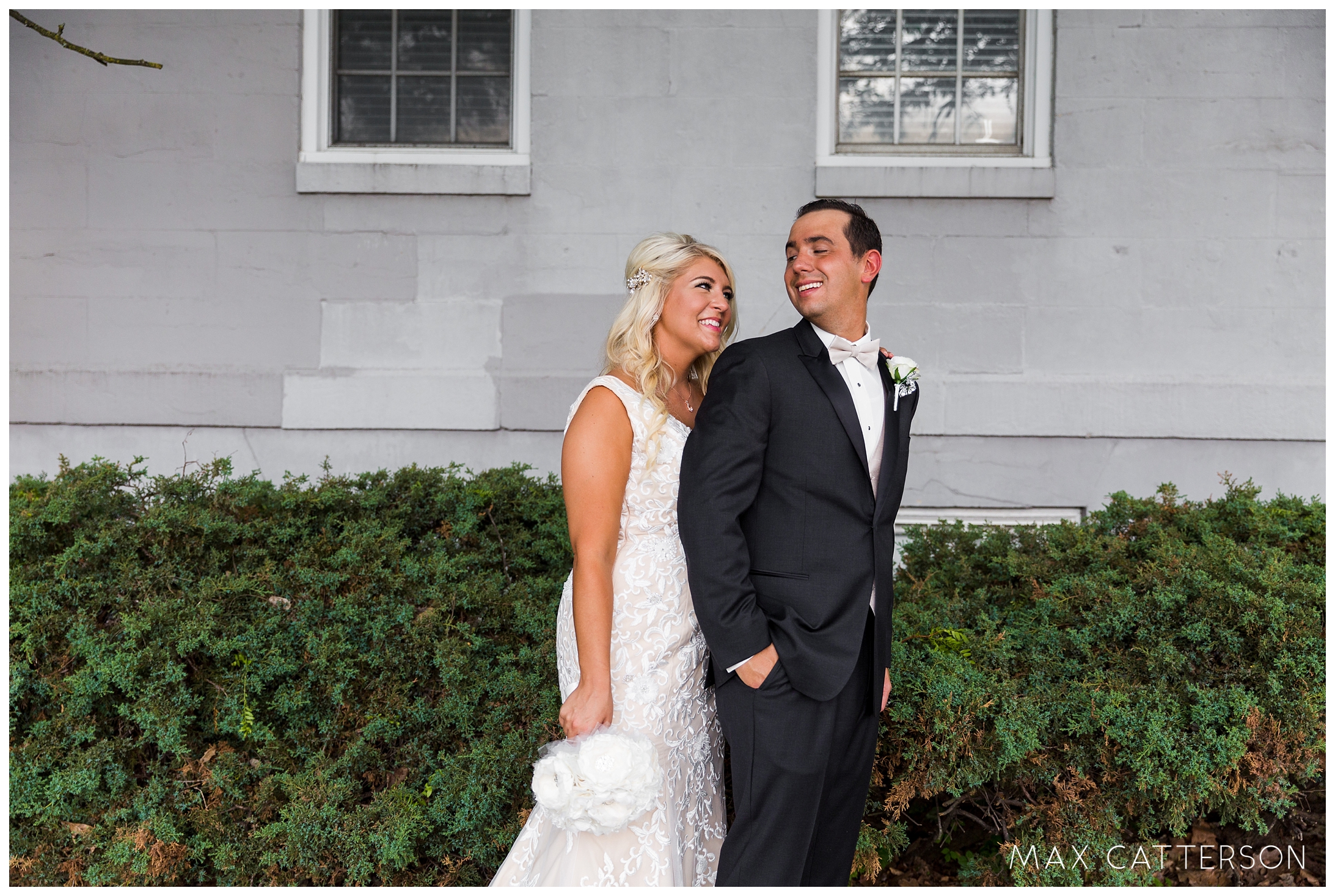 bride and groom in front of wall