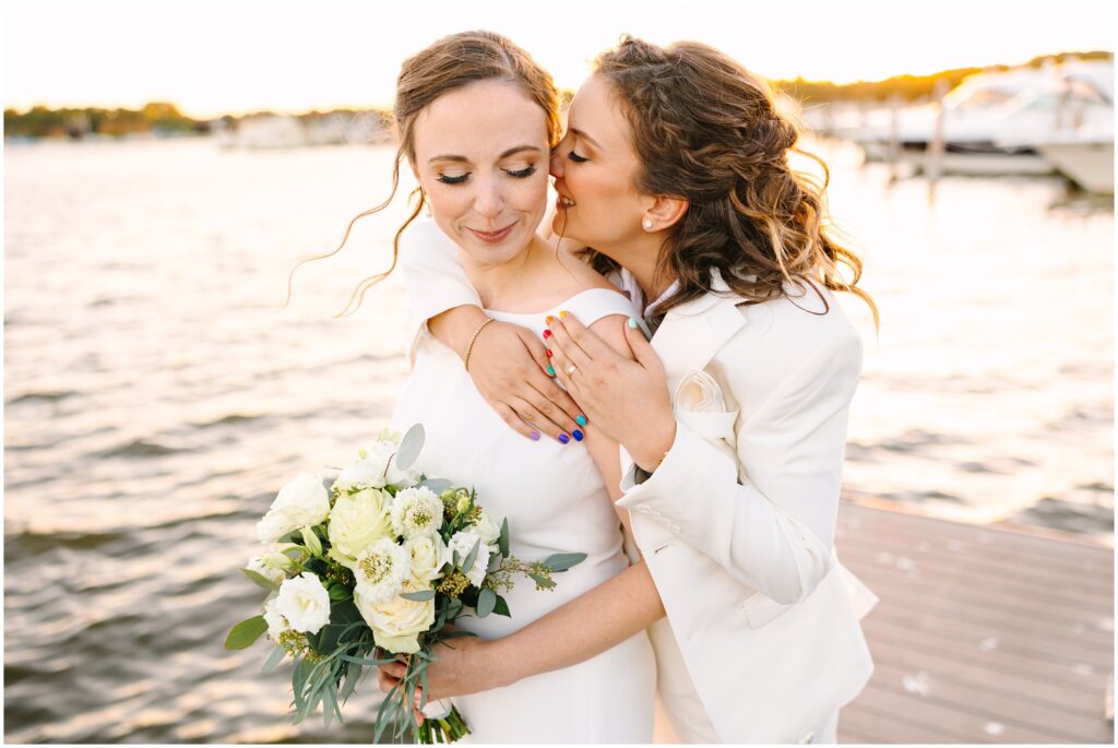 Lesbian couple on their wedding day on a boat doc near a lake at sunset