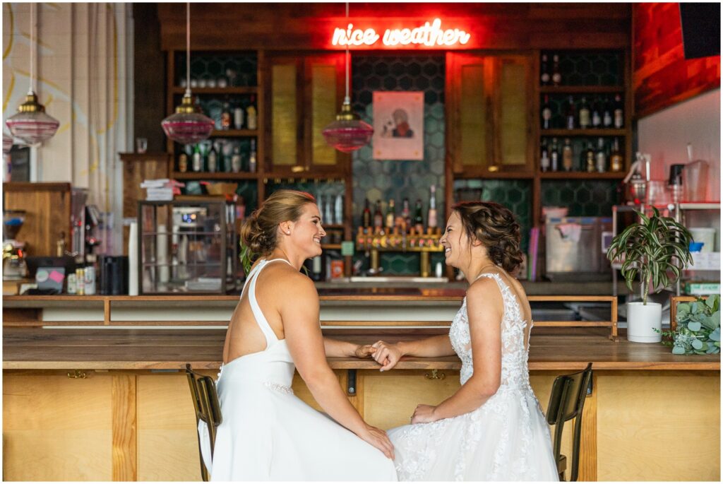 Lesbian couple on their wedding day sitting at a bar